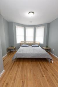 a bedroom with a large bed and two windows at Mins to NYC - Stylish 3 Bedroom Haven in Jersey City