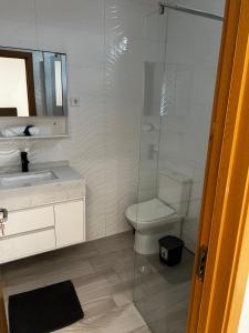 une salle de bain avec toilettes et douche en verre dans l'établissement Pensão Gonçalves, à Calheta