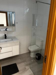 een badkamer met een toilet en een glazen douche bij Pensão Gonçalves in Calheta