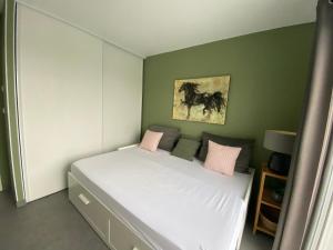 een slaapkamer met een wit bed met roze kussens bij Ama Lur in Hasparren