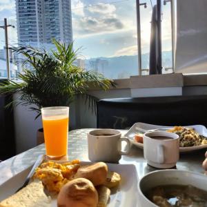 un tavolo con un piatto di cibo e un bicchiere di succo d'arancia di Hotel Alessio a Bucaramanga