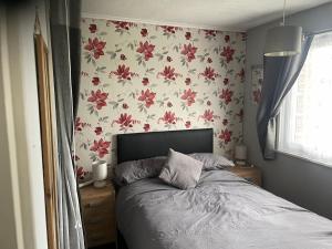 a bedroom with a bed with a floral wallpaper at Captivating 2-Bed Chalet in Great Yarmouth in Great Yarmouth