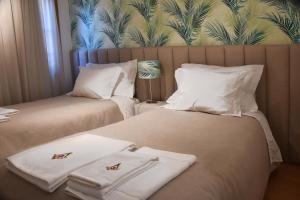 2 Betten in einem Hotelzimmer mit Handtüchern darauf in der Unterkunft Family House Cup in Tomar