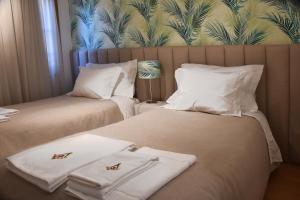 two beds in a hotel room with towels on them at Family House Cup in Tomar +6 photos