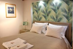 een bed met 2 witte kussens en tropisch behang bij Family House Cup in Tomar