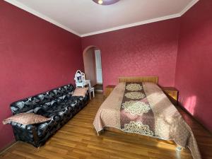 a bedroom with a black leather couch and red walls at Nato & Lado in Sighnaghi