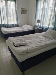 twee bedden in een slaapkamer met twee ramen bij Västervik rum & Stugor in Västervik