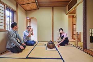 un gruppo di persone seduti sul pavimento in una stanza di KOTO TEA HOUSE - Vacation STAY 12808 a Kumamoto