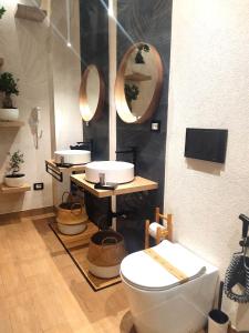 a bathroom with two sinks and a toilet and mirrors at Ti Scialíi Suites Rooms and Relax in Pachino