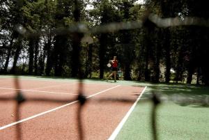 una persona che gioca a tennis su un campo da tennis di Relais Masseria Cardillo a Metaponto