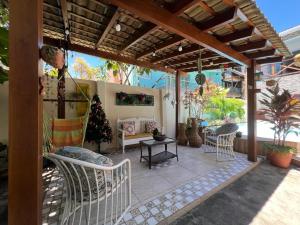 a patio with white chairs and a wooden pergola at Villa Bangalu in Porto De Galinhas