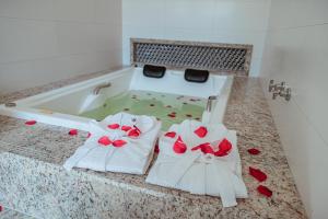 uma banheira com 2 toalhas brancas e rosas vermelhas em Orquídeas Praia Hotel em Porto Seguro