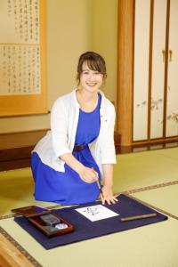 una mujer está sentada en una mesa cortando una foto en KOTO TEA HOUSE - Vacation STAY 12837, en Kumamoto