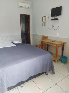 a bedroom with a bed and a desk and a tv at Estrela D Alva Pousada in Pirenópolis