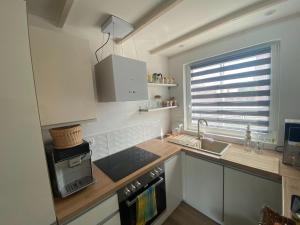 een keuken met witte kasten, een wastafel en een raam bij A comfortable holiday home in Stepniczka in Stepnica