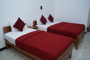 two beds with red and white sheets in a room at Hotel Theevanni Inn in Trincomalee