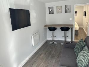 ein Wohnzimmer mit einem TV und 2 Hockern in der Unterkunft Smeaton serviced Accommodation in Liverpool