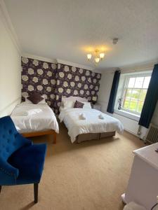 a bedroom with two beds and a blue chair at The Penruddocke Arms in Dinton