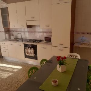 マテーラにあるCasa Vacanza Nonna Doraの白いキャビネットと花のテーブル付きのキッチンが備わります。