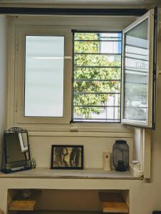 two windows in a room with a shelf with a picture at Ζεστό διαμέρισμα κοντά στο κέντρο της Αθήνας in Athens