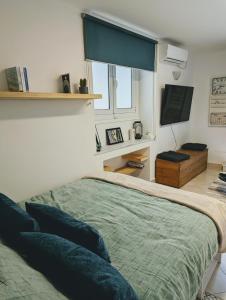 雅典的住宿－Ζεστό διαμέρισμα κοντά στο κέντρο της Αθήνας，一间卧室配有一张带蓝色枕头的床和一扇窗户。
