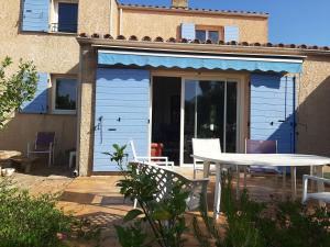 ein blaues Haus mit einem Tisch und Stühlen auf einer Terrasse in der Unterkunft Jolie villa provençale avec piscine et vue mer in La Ciotat