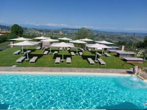 a pool with chairs and umbrellas and a group of tables and chairs at Agriturismo Le Arcate in Sinio