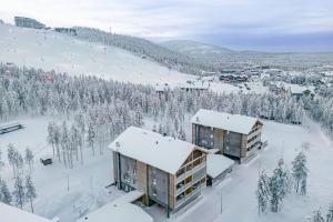 a ski resort with snow covered trees and buildings at Tunturinlaita A4, Ski-in Ski-out 3xbedroom Levi in Kittilä