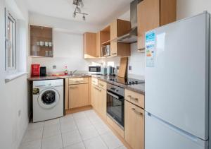 a kitchen with a washer and a white refrigerator at Crawley Maunsell Park Charm & Cosy 1 Bedroom Apartment with Parking in Crawley