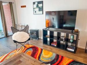 a living room with a flat screen tv and a chair at Cozy Guest House Studio Apartment in Greensboro