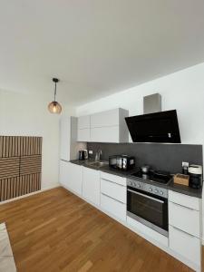 Queens Peak Apartment في كولونيا: مطبخ بدولاب بيضاء وفرن علوي موقد