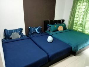 zwei Betten mit blauer Bettwäsche und gefüllten Tieren darauf in der Unterkunft Cozy homestay Ipoh 12 pax at Station 18 in Ipoh