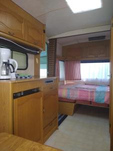 eine Küche und ein Schlafzimmer mit einem Bett in einem Wohnwagen in der Unterkunft De Veenborg in Kolham