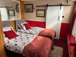 - 2 lits dans une petite chambre aux murs rouges dans l'établissement Seaview Cottage 24 Freeman Street, à Wells-next-the-Sea