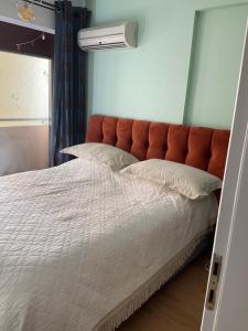 ein Bett mit einem orangefarbenen Kopfteil in einem Schlafzimmer in der Unterkunft Luxury apartment in the elite area in Athen