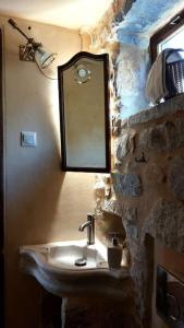 a stone bathroom with a sink and a mirror at Studio Tsiliviani in Loukádhika
