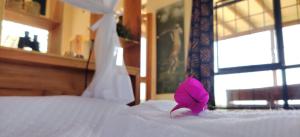 una flor rosa sentada encima de una cama en Harry's Cabin - Overlooking Lake Victoria - 30 min from Jinja, en Jinja