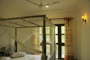 - une chambre avec un lit à baldaquin et une fenêtre dans l'établissement Lion House, à Galle