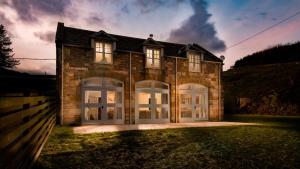 a large brick house with two garage doors at The Coach House, Pentland Hills in Nine Mile Burn