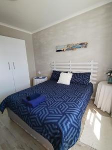um quarto com uma cama com um edredão azul e branco em Intimi2 em Yzerfontein
