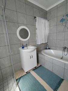 uma casa de banho com um lavatório, uma banheira e um espelho. em Intimi2 em Yzerfontein
