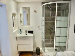 uma casa de banho branca com um chuveiro e um lavatório. em Le Hublot em Le Touquet-Paris-Plage