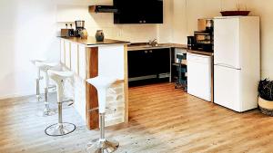 eine Küche mit einem Kühlschrank und 2 Barhockern in der Unterkunft Maison de 2 chambres avec jardin clos et wifi a Sainte Genevieve les Gasny in Sainte-Geneviève-lès-Gasny