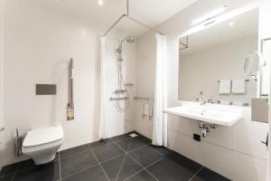 a white bathroom with a toilet and a sink at IntercityHotel Breda in Breda
