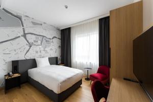 une chambre d'hôtel avec un lit et un fauteuil rouge dans l'établissement IntercityHotel Breda, à Breda