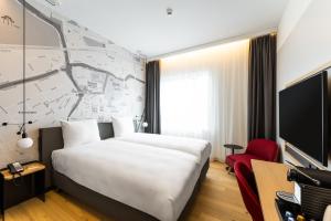 um quarto de hotel com uma cama e uma televisão em IntercityHotel Breda em Breda
