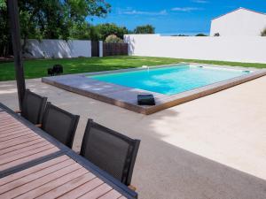 a large swimming pool with two chairs and a table at Beautiful Villa close to the Seaside in Talmont