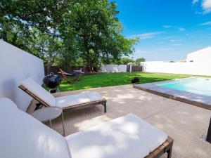 a patio with two chairs and a dog and a pool at Beautiful Villa close to the Seaside in Talmont