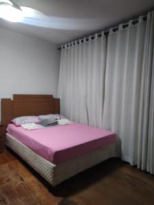 a bed in a room with white curtains at Casa de 3 quartos in Resende