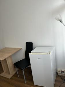 a desk with a chair next to a white refrigerator at HOSTEL Bahnhof in Frankfurt